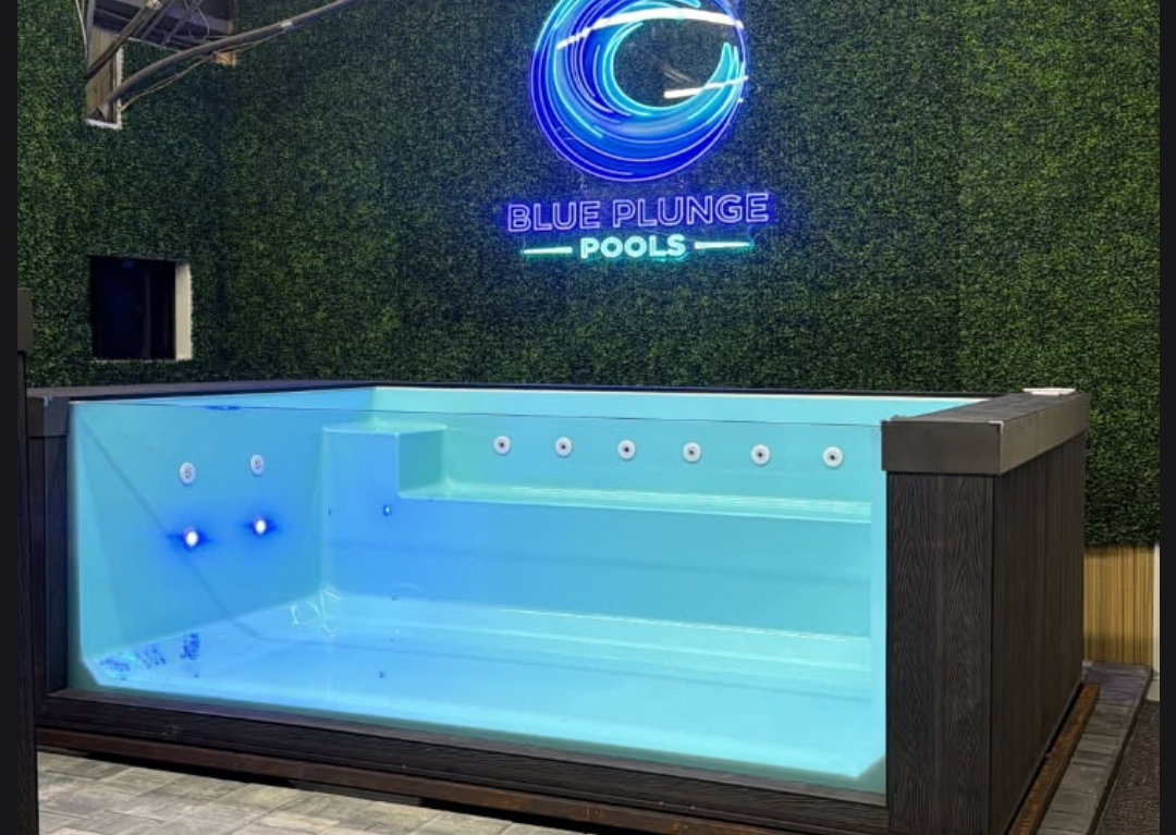 The Retreat show shell indoors, lit, under a neon Blue Plunge Pools sign.