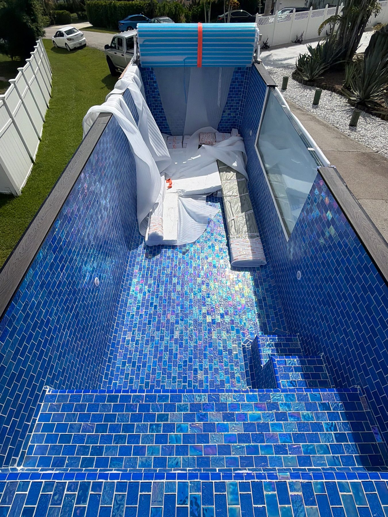 A mosaic shell during install, steps in the foreground, cover stacked at the far end, protective sheets still inside.