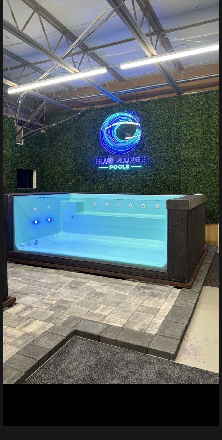 The Retreat show model indoors, under a neon Blue Plunge Pools sign.