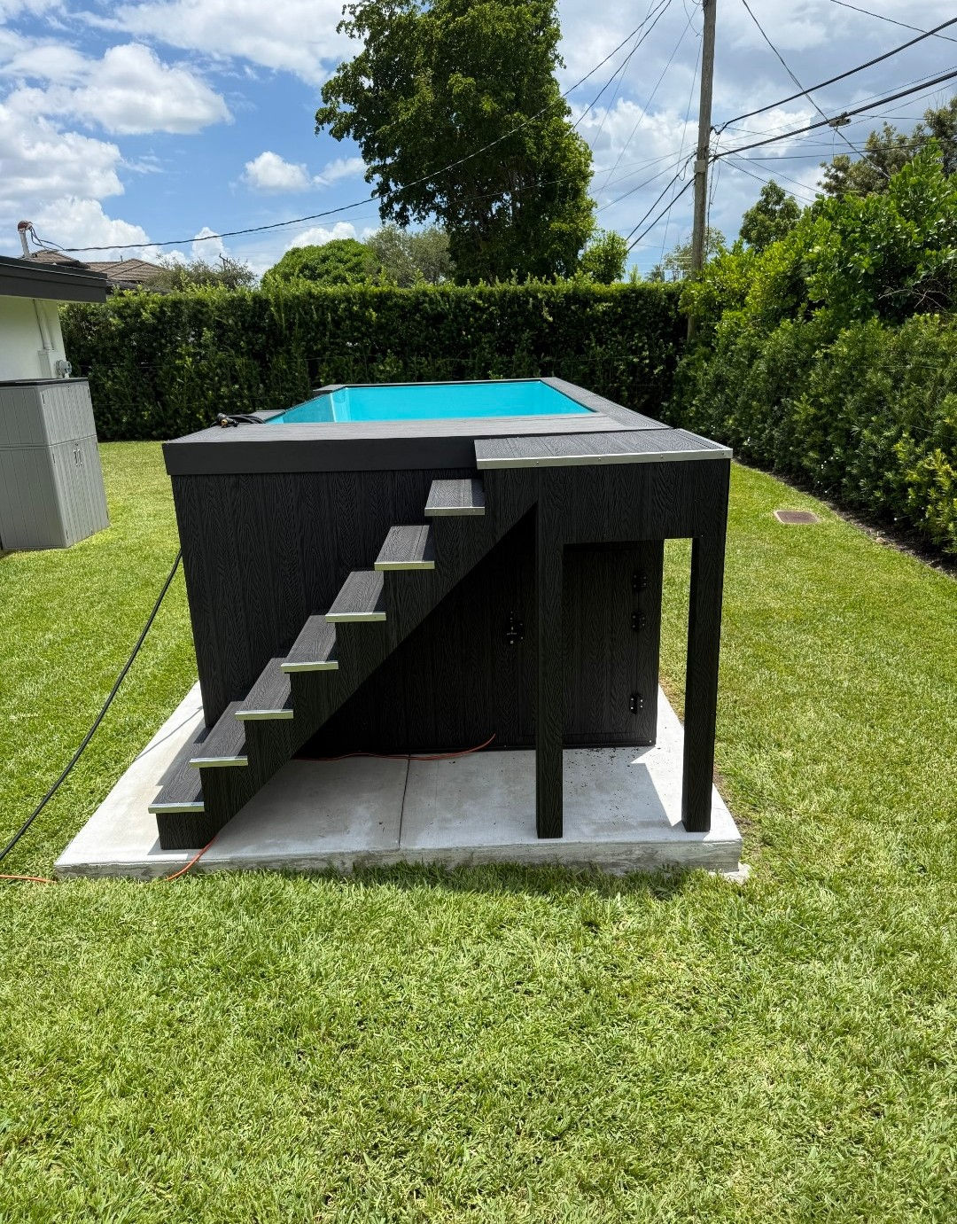 Stairs climbing the side of a dark plunge pool on a concrete pad.