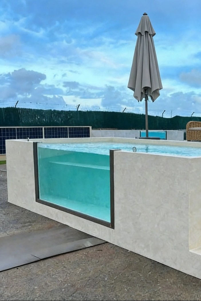 A light stone-clad plunge pool with a tall acrylic window.